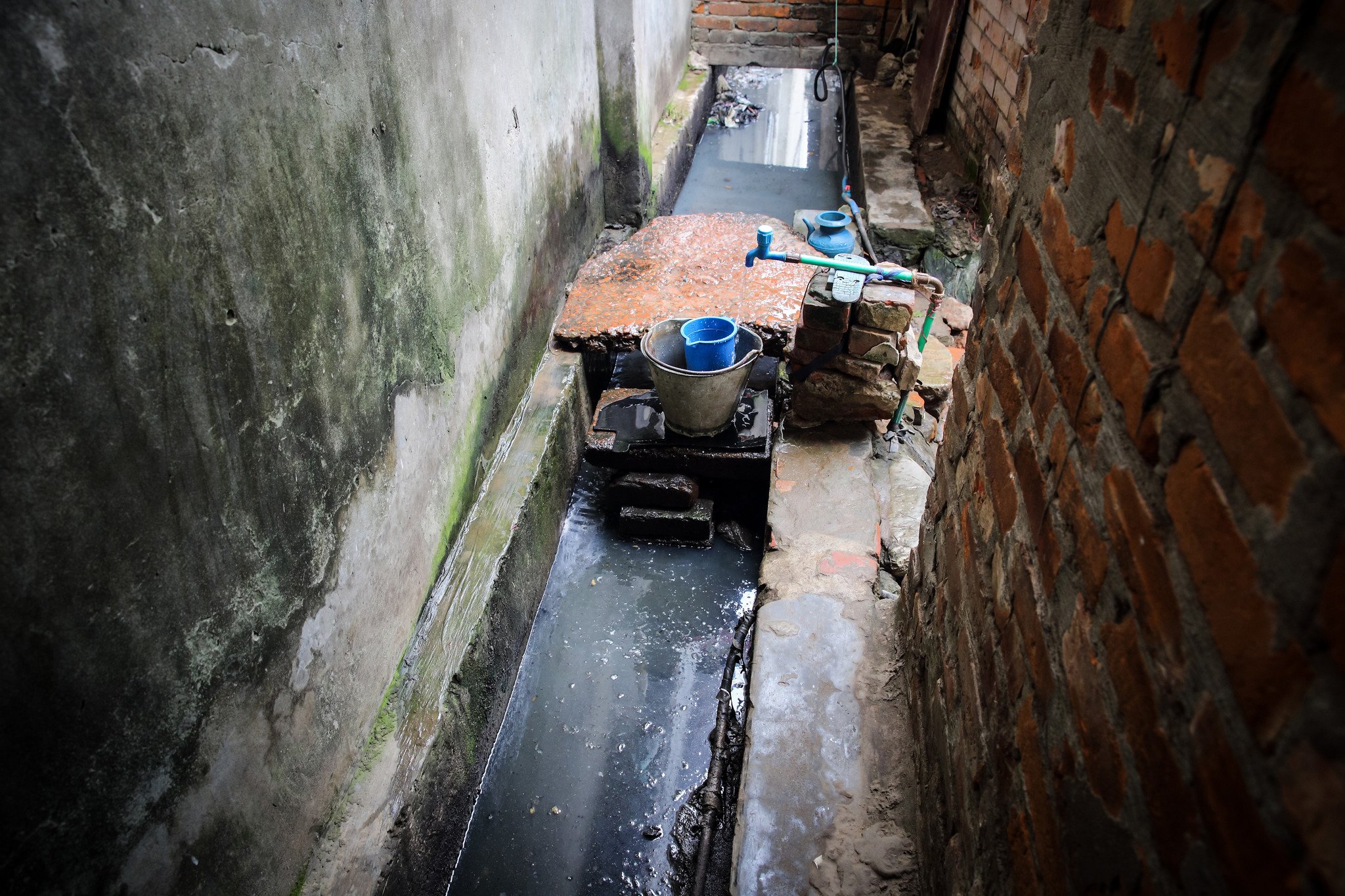 A channel of filthy waste runs through the narrow yard where they bathe, prepare meals and wash and dry their clothes. In rainy season this overflows, flooding their homes. (Photo: GMB Akash)